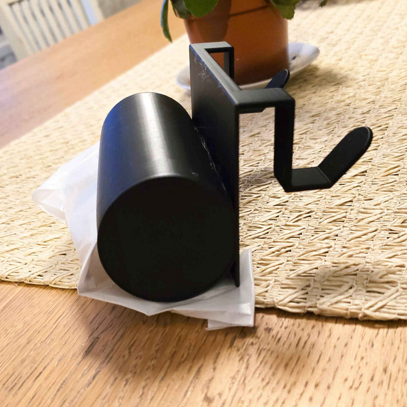 Musta jätepussiteline keittiön pöydällä, jossa roskapussi valmiiksi asetettuna. Kätevä säilytysratkaisu oviin ja laatikoihin.