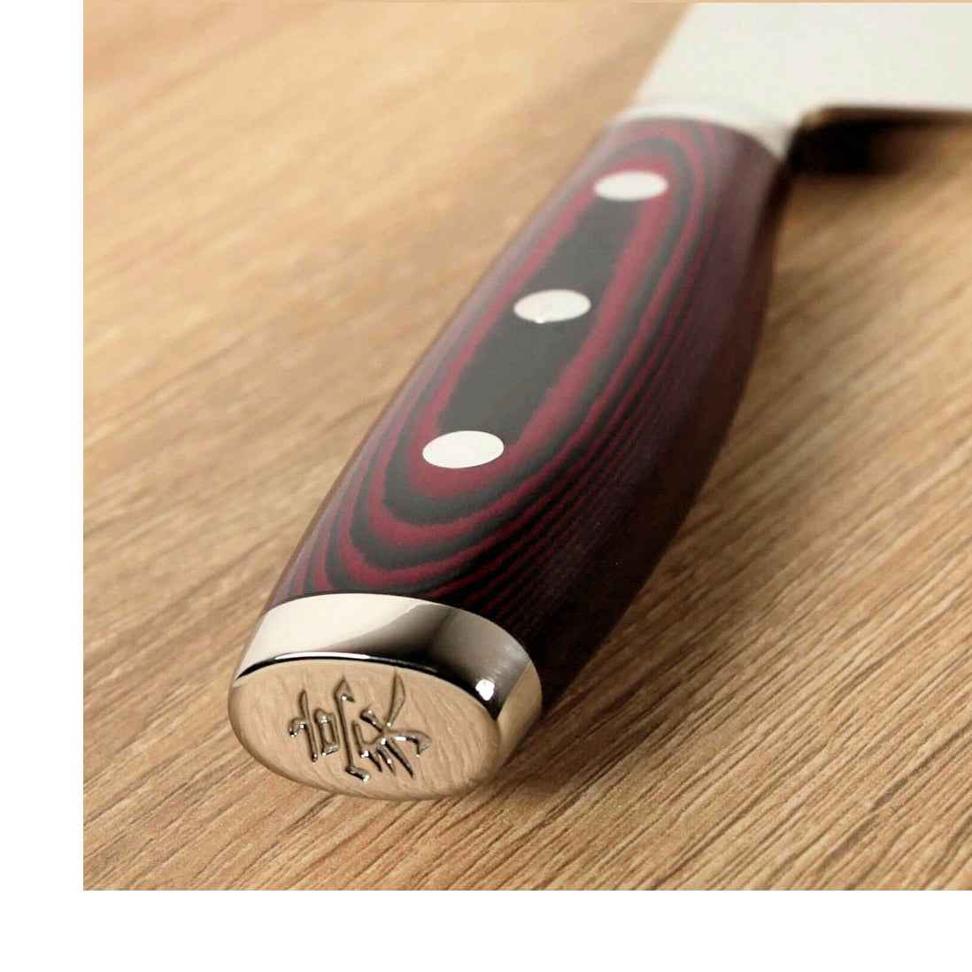 Yaxell Super Gou Kiritsuke kokkiveitsi - Ainutlaatuinen Laatu, lähikuva veitsen punamustasta kahvasta ja kaiverruksella varustetusta päädystä.