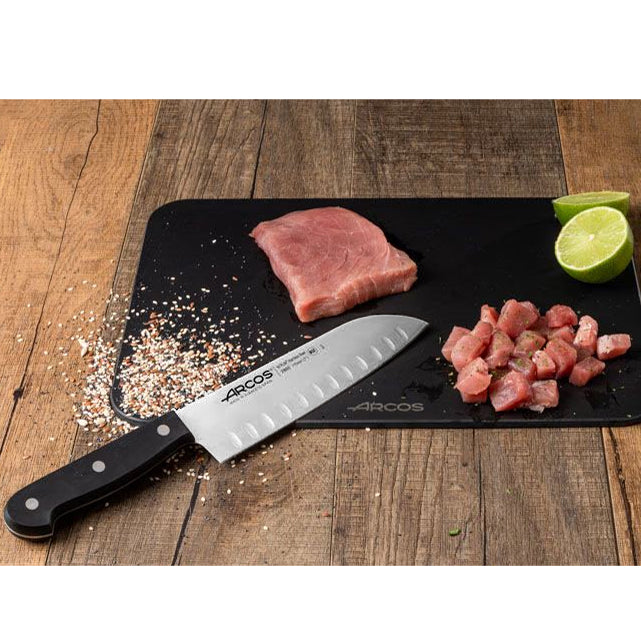 Arcos Santoku Ovaalihiottu, 17 cm - Laatuveitsi Ammattilaisille, leikkuulaudalla porsaanlihan ja limen kanssa, korostaen veitsen tarkkuutta.