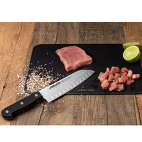 Arcos Santoku Ovaalihiottu, 17 cm - Laatuveitsi Ammattilaisille, leikkuulaudalla porsaanlihan ja limen kanssa, korostaen veitsen tarkkuutta.