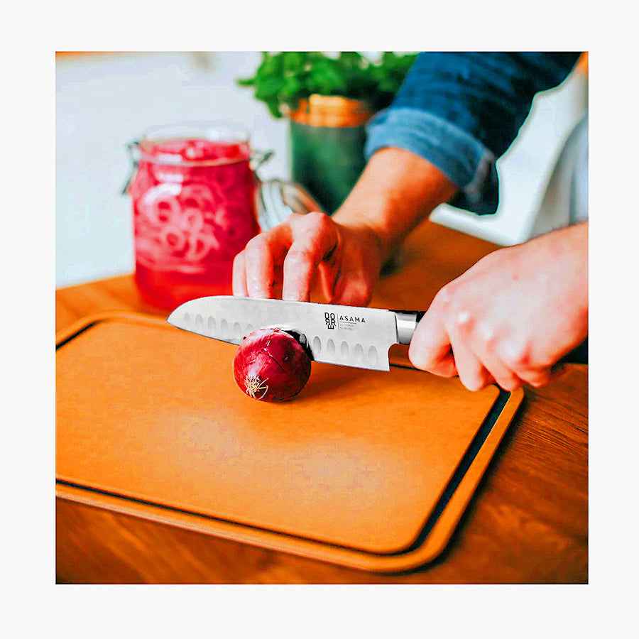 Henkilö leikkaa sipulia Dorre Sami puukuitu leikkuulaudalla. Erinomainen valinta hygieniseen ja tehokkaaseen ruoanvalmistukseen.