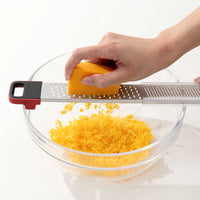 Cuisipro SGT Deluxe Dual Raastin raastamassa cheddarjuustoa kulhoon, kaksipuolinen keittiöväline arjen ruoanlaittoon ja leivontaan.