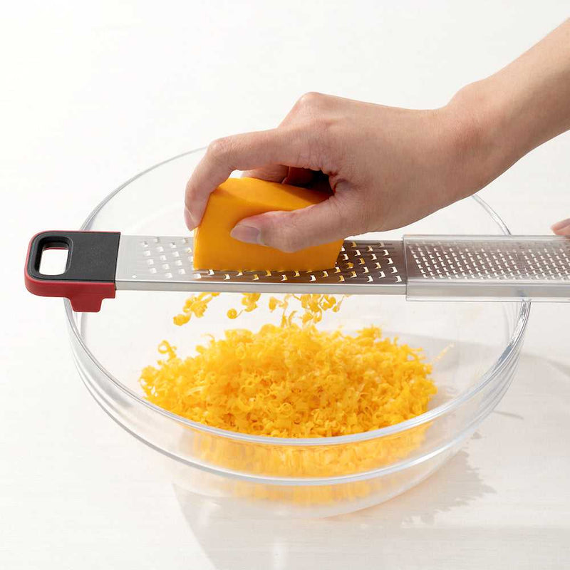 Cuisipro SGT Deluxe Dual Raastin raastamassa cheddarjuustoa kulhoon, kaksipuolinen keittiöväline arjen ruoanlaittoon ja leivontaan.