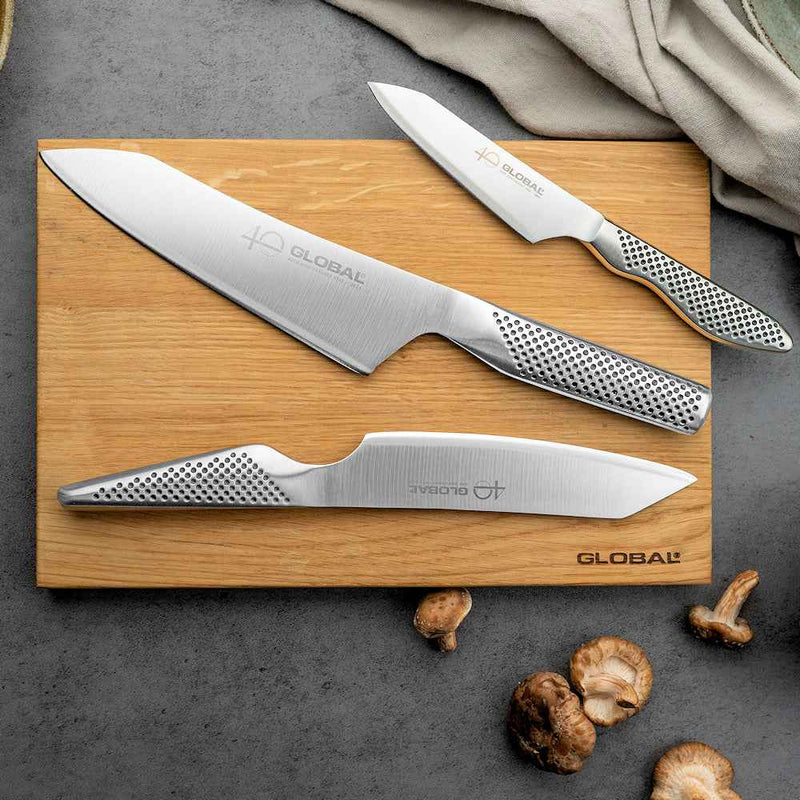 Global 40 v. juhlasetin veitsisetti puualustalla – kolme Global-veistä ja sienet puupöydällä.