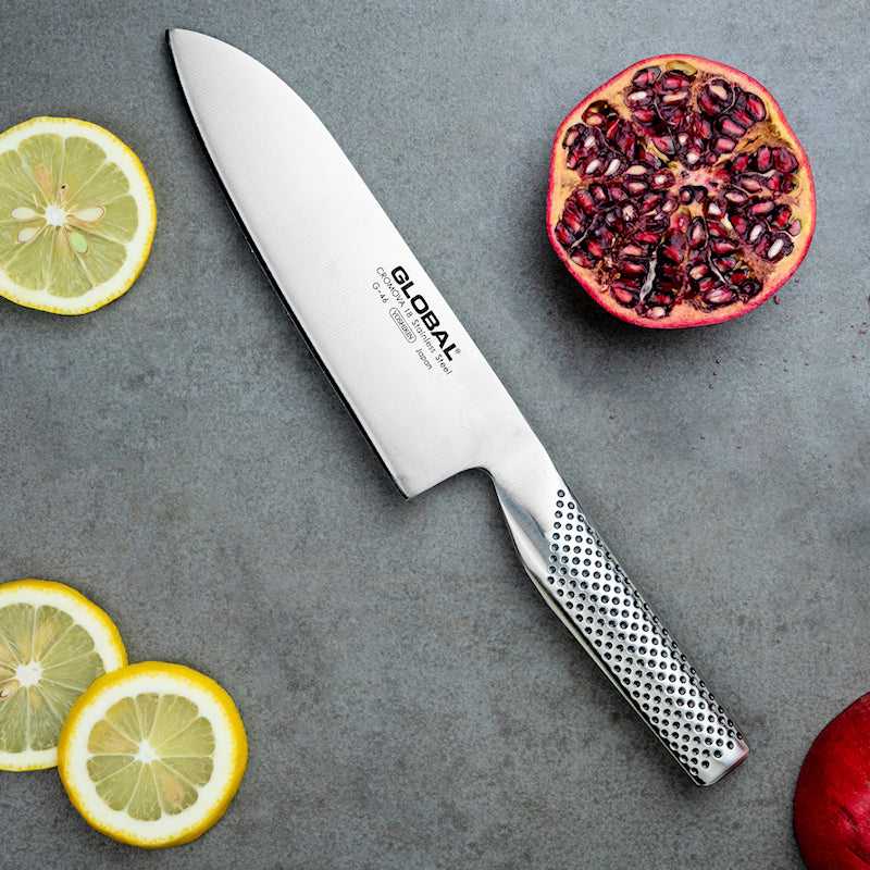 Global G-46 santokuveitsi 18 cm aseteltuna hedelmien kanssa. Japanilainen veitsi sopii vihannesten, kalan ja lihan leikkaamiseen.