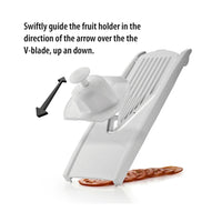 Börner Turvapidike mandoliiniin valkoinen kiinnitettynä V-leikkuriin, viipaloitu tomaatti alla. Turvapito suojaa sormia ruoanlaitossa.