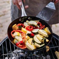 Skottsberg Paistinpannu 20 cm grillikäytössä, täynnä värikkäitä vihanneksia, täydellinen hiiliteräspannu ulkokokkaukseen ja grillaamiseen.