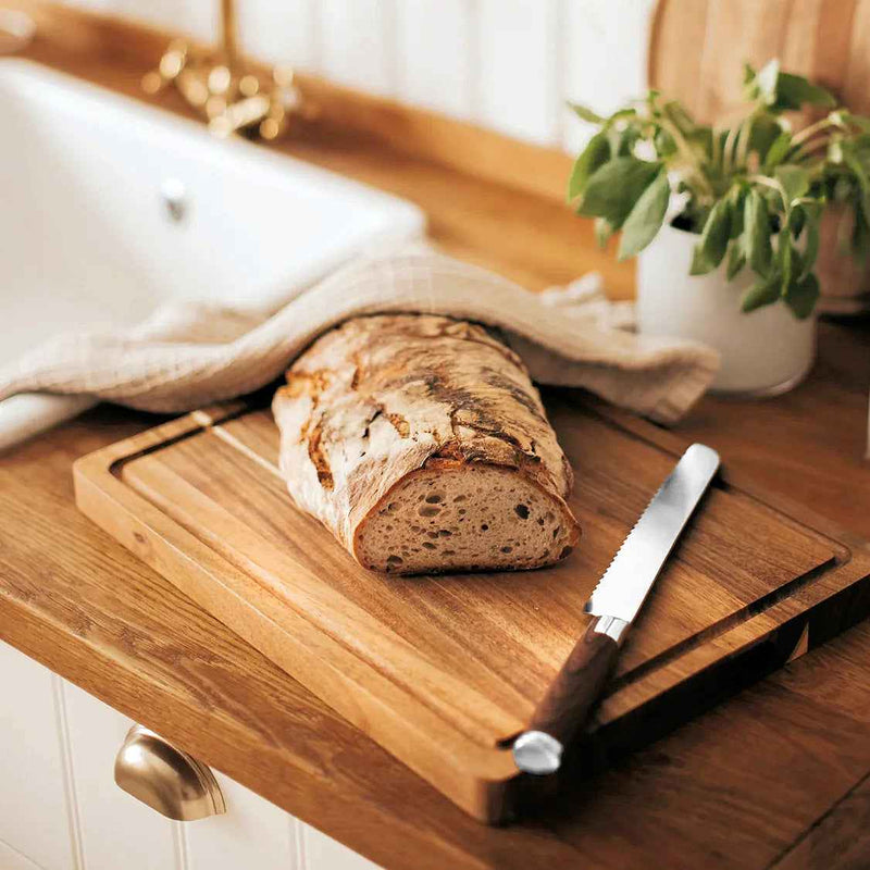 Dorre Skye leikkuulauta akasiapuusta keittiössä, leivän ja veitsen kanssa. Tyylikäs ja käytännöllinen keittiötarvike.