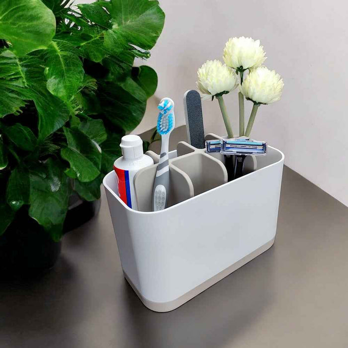 Kylpyhuoneteline - Kylpyhuoneen järjestelijä harmaavalkoisena, täytettynä hygieniatarvikkeilla kuten hammasharja ja partahöylä, modernilla kylpyhuonetason pinnalla.