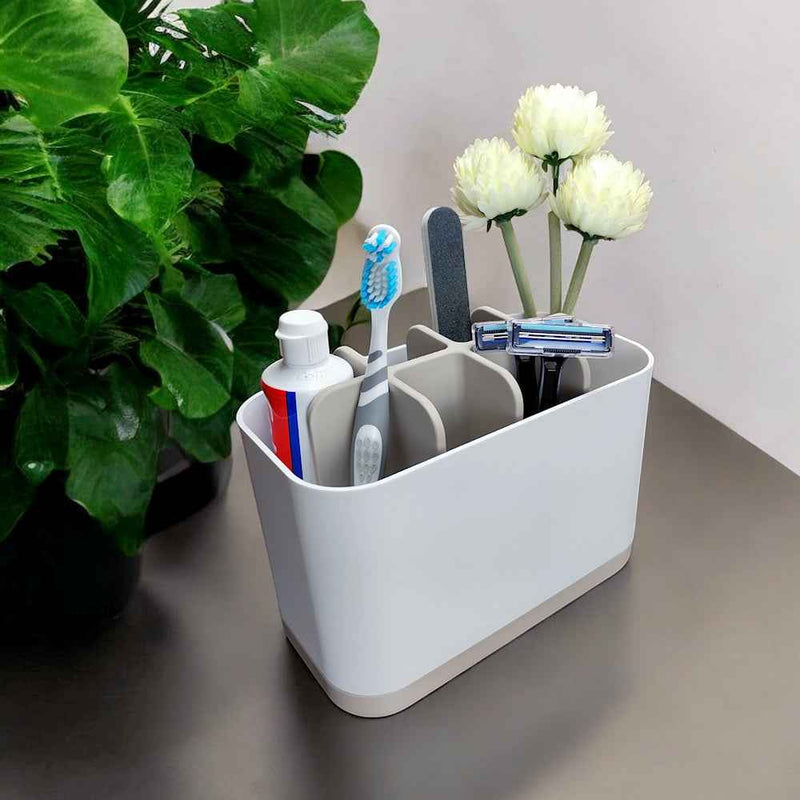 Kylpyhuoneteline - Kylpyhuoneen järjestelijä harmaavalkoisena, täytettynä hygieniatarvikkeilla kuten hammasharja ja partahöylä, modernilla kylpyhuonetason pinnalla.