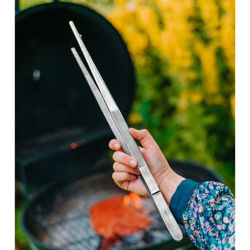 Grilli Atulat 40cm käytössä grillin äärellä. Pitkät, ruostumattomat atulat sopivat tarkkaan ja turvalliseen grillaamiseen ulkona.