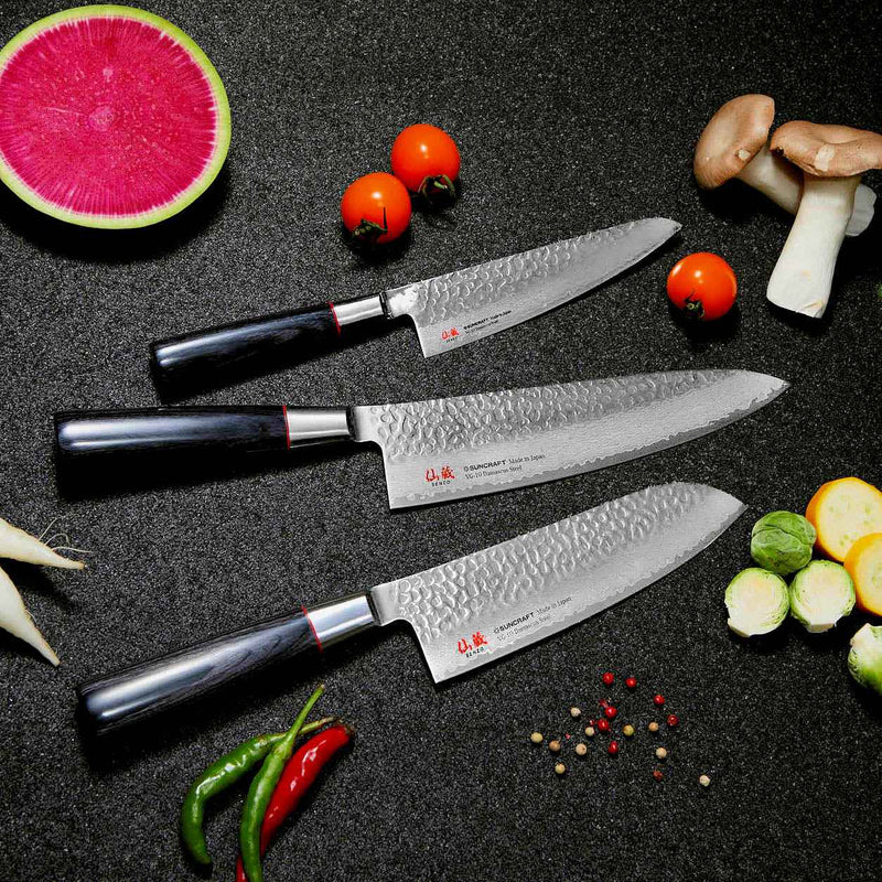 Suncraft Senzo Santoku - 33 kerrosta Damascus-terästä, 16,7 cm, valmistettu Japanissa. Tyylikäs kokkiveitsi vihannesten keskellä mustalla taustalla.