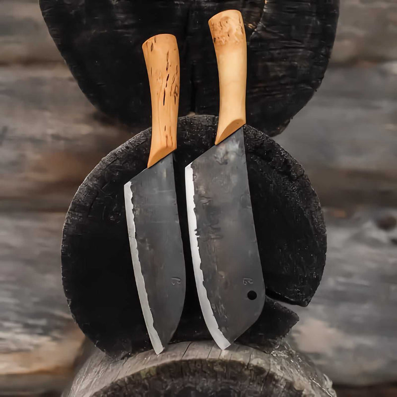 Kaksi Laatupuukko kokkiveistä aseteltuna puupölkylle. Hiiliteräksiset terät ja visakoivukahvat korostavat käsityön laatua.