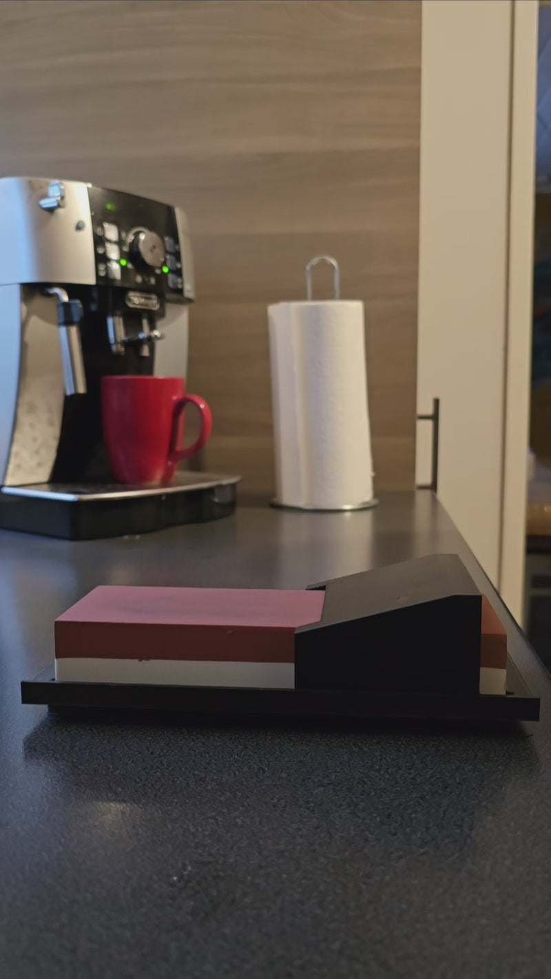 Kulmaohjain teroituskivelle keittiön työtasolla, taustalla kahvinkeitin ja punainen muki, käytännöllinen keittiövaruste veitsien teroitukseen