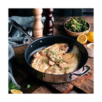 Stellar pinnoitettu paistokasari 28 cm käytössä, paistettu kala ja yrtit pannulla. Laadukas keittiöväline ruoanlaittoon kotikokeille.