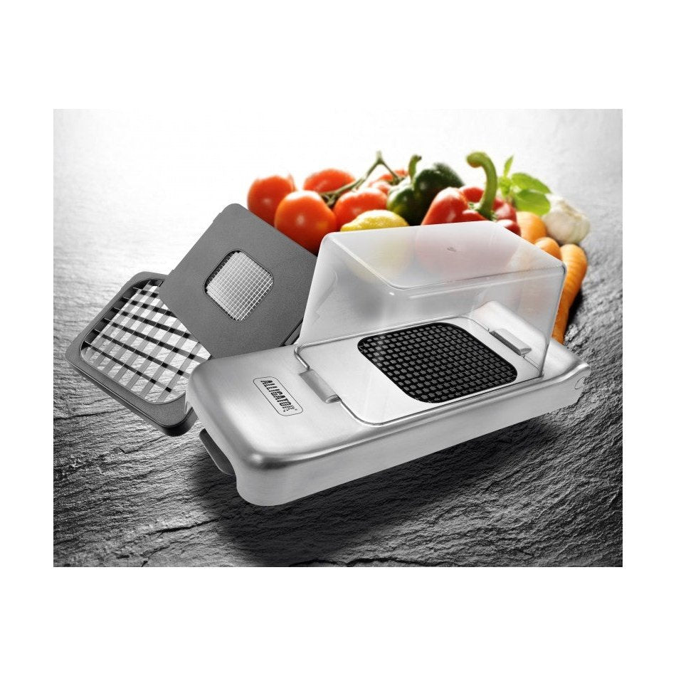 Monikäyttöinen Alligator vihannesleikkuri ruostumattomasta teräksestä vaihdettavilla terillä ja vihanneksilla taustalla.