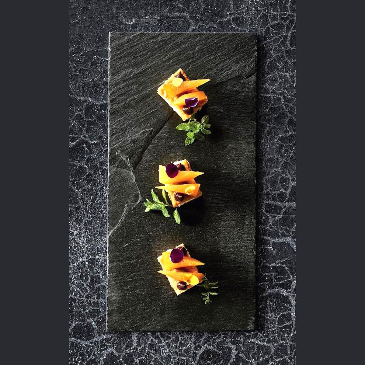 Lacor Kivitarjotin 20x15 cm - Kivitarjotin esillepanossa. Tarjoilualustalla kolmen annoksen sushit tai juustot koristeineen.