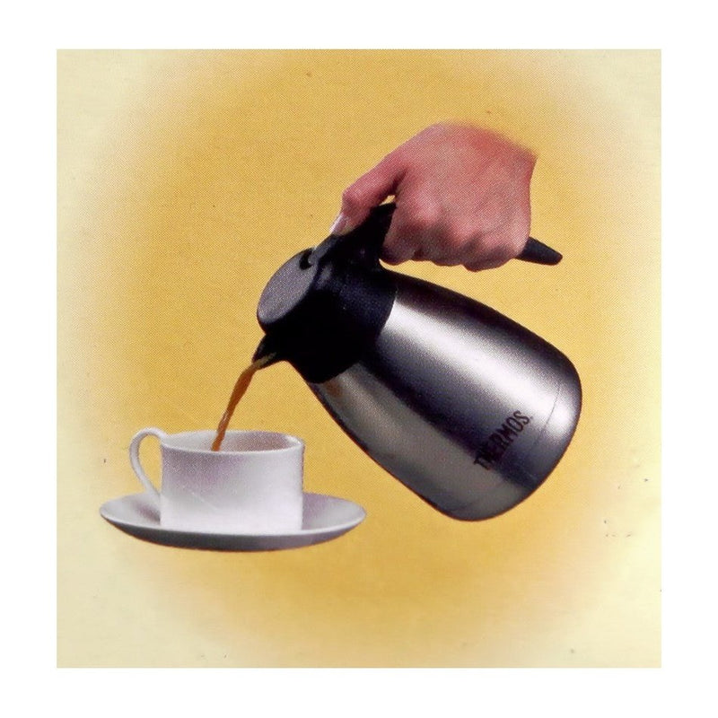 Käytössä oleva Thermospannu Brasilia TGS-600 0,6 L - Termoskaadin, josta kaadetaan kuumaa juomaa valkoiseen kuppiin.