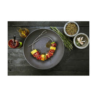 Joustavat grillivartaat tarjoiluvalmiina lautasella, mukana mausteita ja kastikkeita, ihanteellinen keittiöväline grillaamiseen.