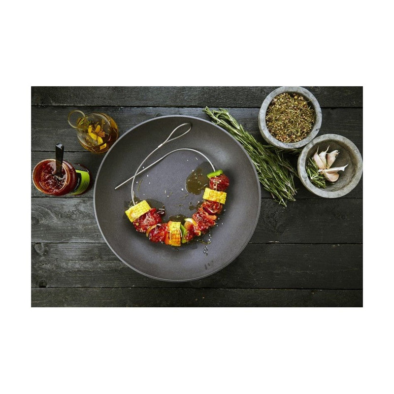 Joustavat grillivartaat tarjoiluvalmiina lautasella, mukana mausteita ja kastikkeita, ihanteellinen keittiöväline grillaamiseen.