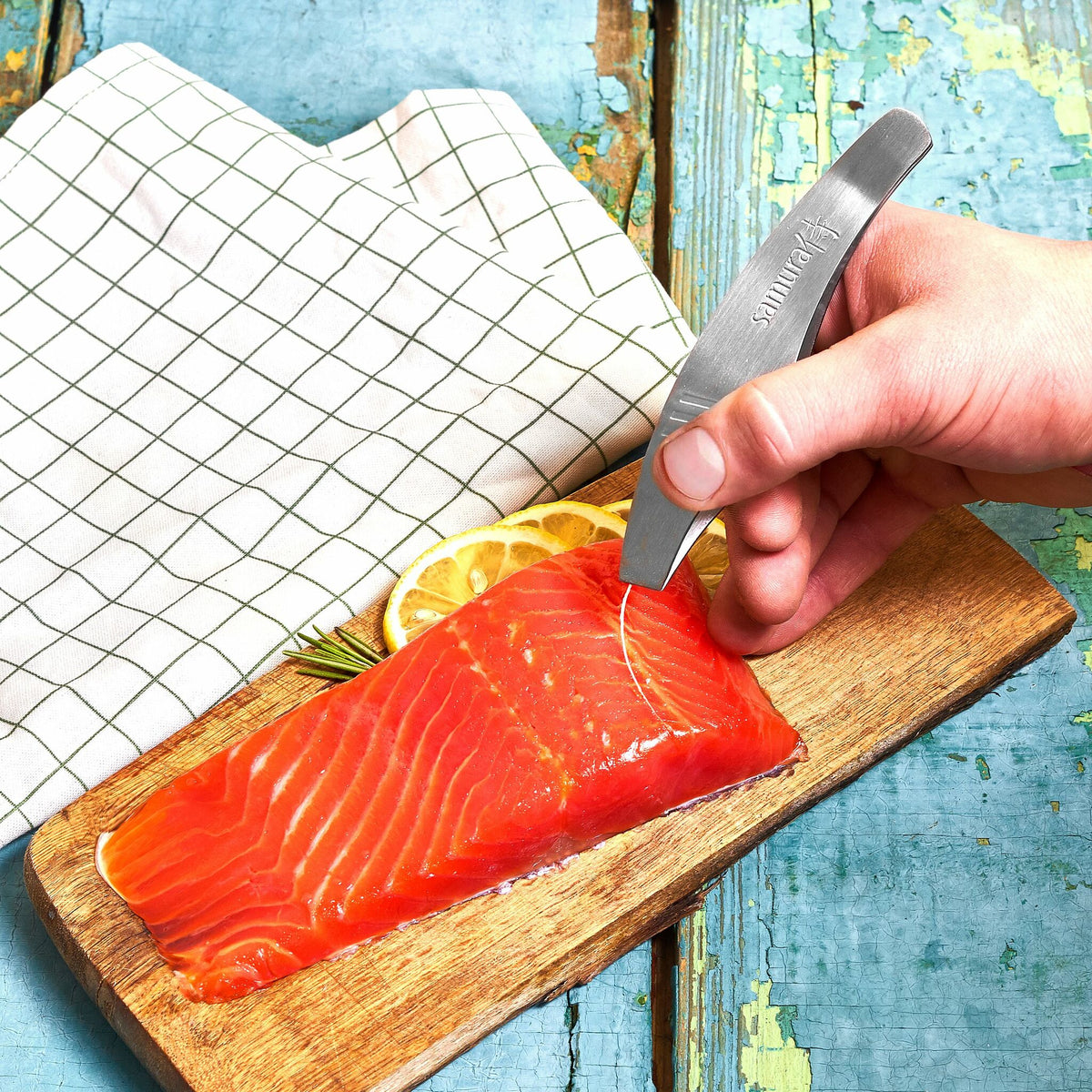 Käsi käyttää Samura Ruotopinssejä 13 cm lohifileen ruotojen poistamiseen, AUS-10 teräs takaa kestävyyden ja tarkkuuden.