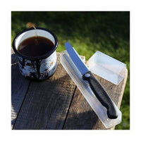 Victorinox taittuva eväsveitsi retkellä puupöydällä kahvimukin vieressä, mukana säilytyskotelo helppoon kuljetukseen.