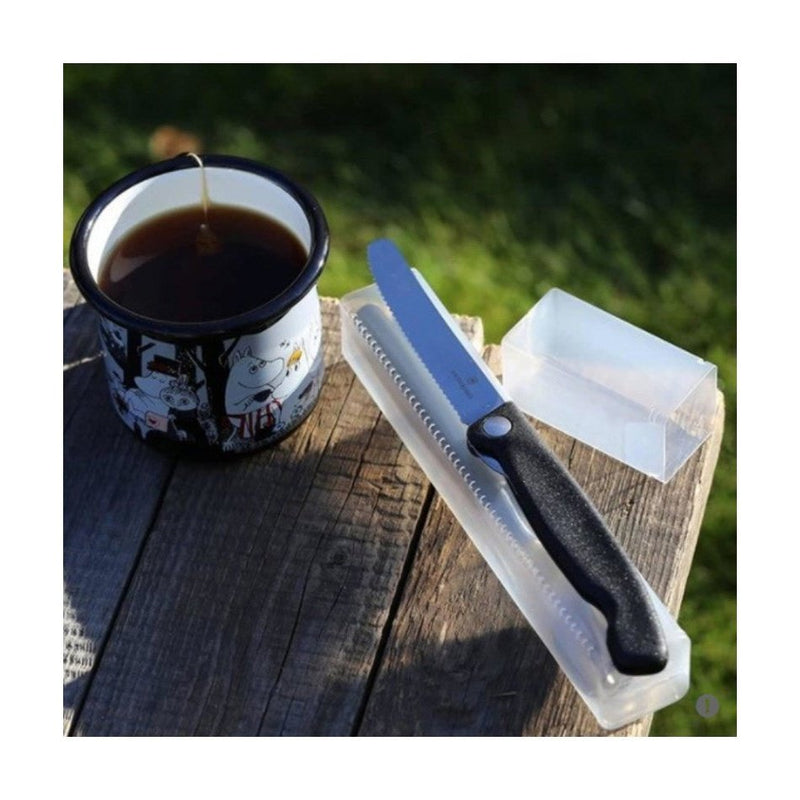 Victorinox taittuva eväsveitsi retkellä puupöydällä kahvimukin vieressä, mukana säilytyskotelo helppoon kuljetukseen.