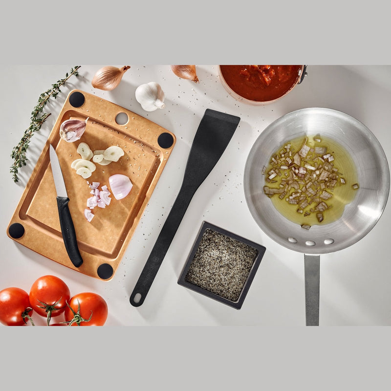 Victorinox Puukuitu Leikkuulauta ruskea käytössä keittiössä, leikkuupinta valkosipulille ja veitselle, osa modernia ruoanlaittoa.