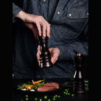 Henkilö käyttämässä London Suolamyllyä, jauhamassa suolaa ruokaan, tumman ruskea pyökkipuu ja ergonominen muotoilu.